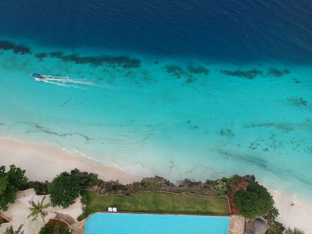 Vista aérea de piscina infinita frente al mar turquesa de Zanzíbar